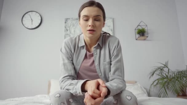 mujer preocupada con las manos apretadas sentada en la cama - Metraje, vídeo