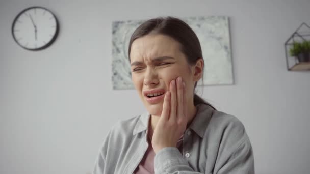 junge Frau berührt Wange, während sie unter Zahnschmerzen leidet - Filmmaterial, Video