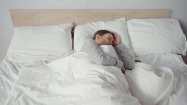 mujer joven que tiene insomnio mientras está acostada en la cama - Imágenes, Vídeo