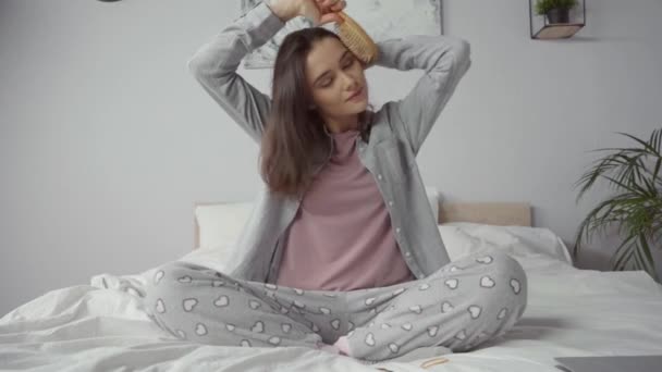 動揺した女性がベッドに座って髪をブラッシング - 映像、動画