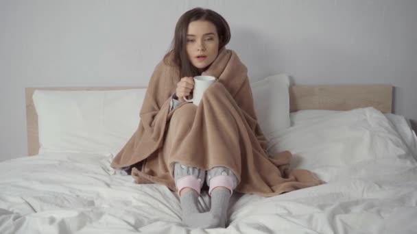 zieke vrouw bedekt met deken houden kopje thee - Video