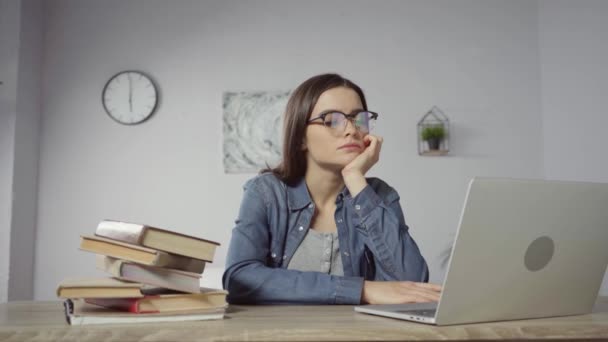 mladá žena v brýlích pomocí notebooku v blízkosti knih na stole - Záběry, video