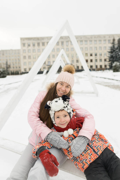 Щаслива родина сидить на білому снігу в зимову погоду
 - Фото, зображення