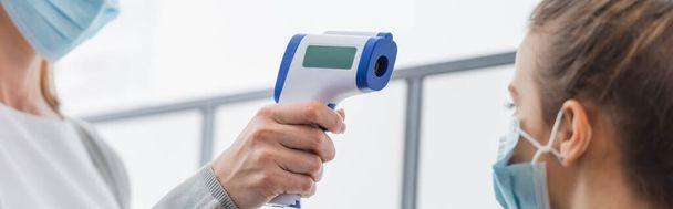 Enseignant mesurant la température de la pupille avec thermomètre sans contact au premier plan flou, bannière  - Photo, image