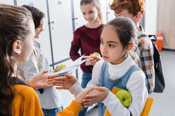 Les filles jouant jeu de galette près de camarades de classe avec des pommes et des cahiers sur fond flou à l'école  - Photo, image
