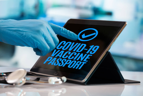 Иммунитет, прививки и концепция цифрового паспорта. Врач нажимает на кнопку паспорта вакцинации коронавируса ковид-19 на цифровом экране. Рука врача, нажимающего на кнопку на планшете, который авторизирует цифровой паспорт вакцинации Covid-19 для  - Фото, изображение