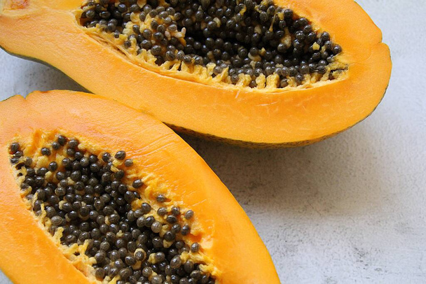 Yarı sulu papaya, içinde tohum olan iki yarım papaya, vitamin dolu portakal meyvesi, sağlıklı beslenme. - Fotoğraf, Görsel