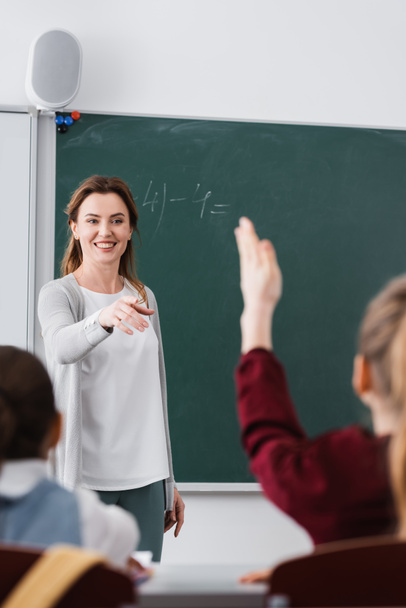 professor feliz apontando para estudante levantando a mão em primeiro plano desfocado - Foto, Imagem