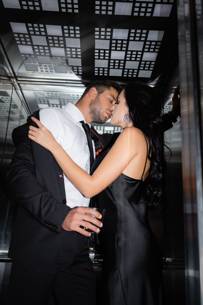 若いです女性undressingボーイフレンドとともにガラスのウィスキーでエレベーター  - 写真・画像