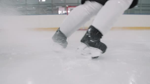 Alhainen osa hidas tunnistamaton jääkiekkoilija luistimet pysähtyen äkillisesti ja potkiminen jäällä jäällä teräviä teriä - Materiaali, video