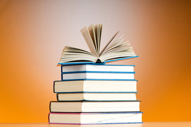 Stack of text books against gradient background - 写真・画像