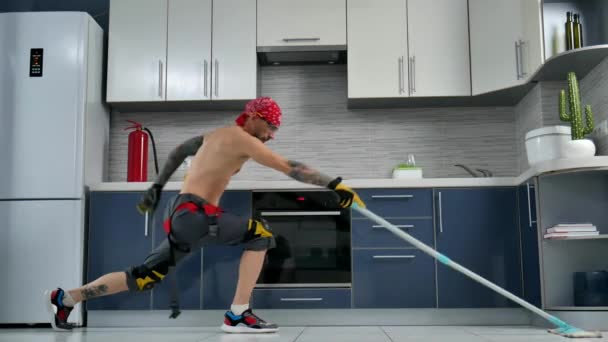Mies, joka on töissä siivousfirmassa, siivoaa keittiön lattian ja tanssii. - Materiaali, video