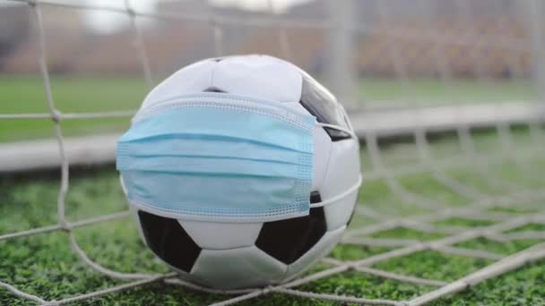 Μπάλα ποδοσφαίρου στην Ιατρική Μάσκα στο Goal Net. Άδειο στάδιο. Ακύρωση ποδοσφαιρικών αγώνων - Πλάνα, βίντεο