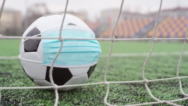 Μπάλα ποδοσφαίρου στην Ιατρική Μάσκα στο Goal Net. Άδειο στάδιο. Ακύρωση ποδοσφαιρικών αγώνων - Πλάνα, βίντεο