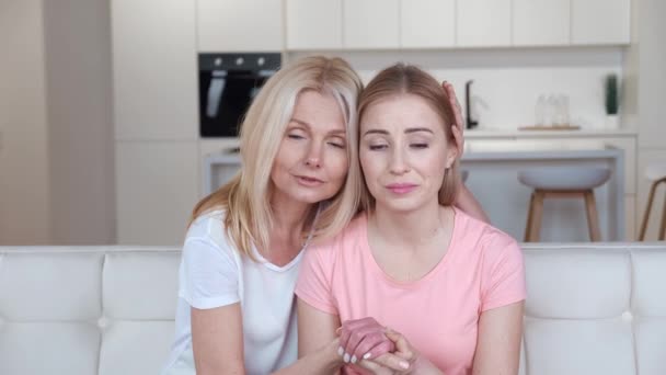 Worried mature mother comforting depressed grown daughter. Caring old mother listening to adult sad daughter sharing problems sitting on the couch at home - Footage, Video