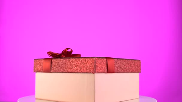 Presenteer doos op kleur regenboog achtergrond. Vakantie geschenkdoos op rotatie 360 tafel - Video