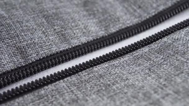 Metallic zipper bag in gray fabric. Plastic black teeth. Macro shot. Hand pulls the cord - Footage, Video