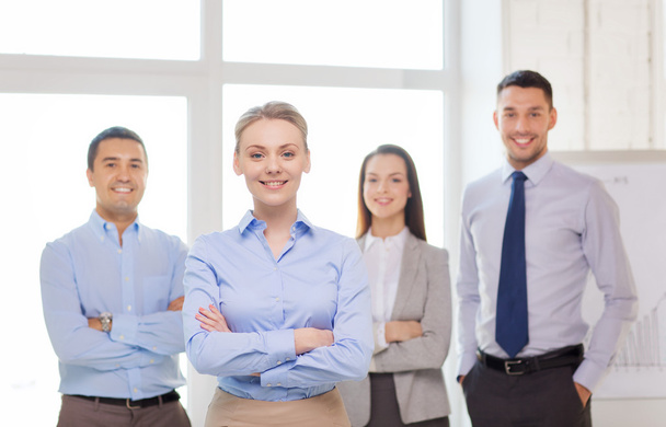Smiling businesswoman in office with team on back - 写真・画像