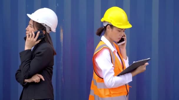 Geschäftsfrau und Fabrikarbeiterin benutzen Smartphone und sprechen. Arbeiter kommunizieren über Technologie-Telefone, um Arbeitsprozesse zu steuern. - Filmmaterial, Video