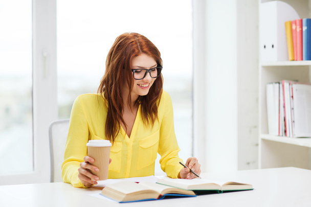 Smiling student girl reading books in library - Foto, imagen