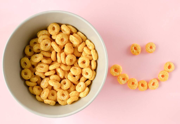 Bowl of breakfast cereal in pink background. Healthy Cereal Rings. Space for text. Top view. Flat lay. - Photo, Image