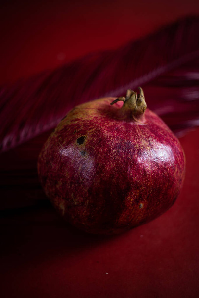 a red pomegranate lies on a red background - Фото, изображение