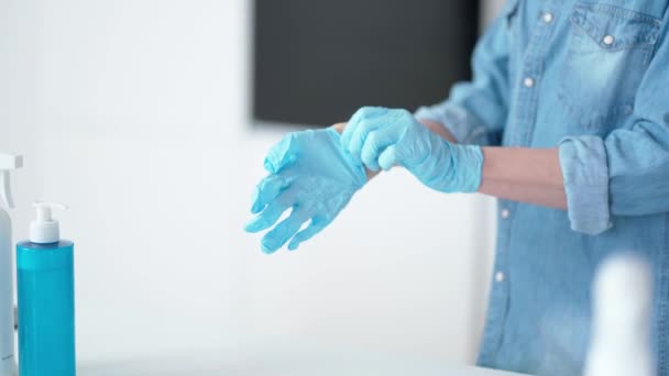 Bereiten Sie sich auf die Aufräumarbeiten vor. Großaufnahme der Hände der Hausfrau, die ihre schützenden blauen Handschuhe anzieht, bereit, mit der Hausreinigung zu beginnen - Filmmaterial, Video
