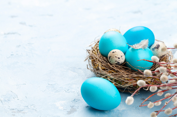 Πολύχρωμα πασχαλινά αυγά στη φωλιά σε πέτρινο φόντο. Με χώρο για τους χαιρετισμούς σου - Φωτογραφία, εικόνα