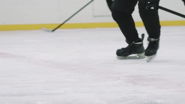 PAN de bajo ángulo con lentitud de jugador de hockey irreconocible golpeando disco con palo y otros jugadores tratando de ganar el control sobre él, patinaje en la arena de hielo interior - Metraje, vídeo