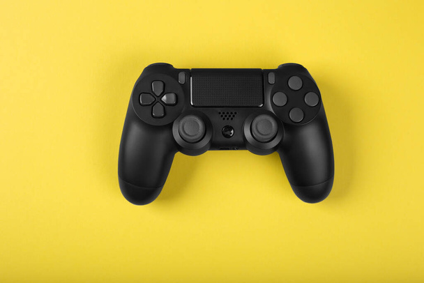 Black gamepad isolated on a yellow background. Gaming concept. Close up - Photo, Image