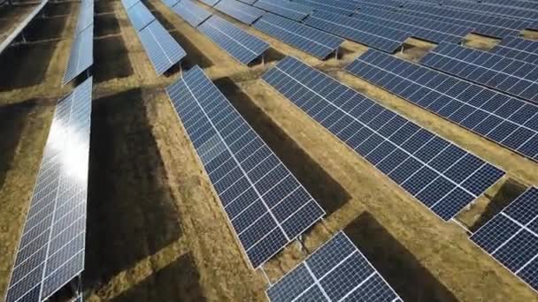 Naperőmű egy mezőn egy napsütéses napon. Madártávlatból. A napelemek sorban állnak az energiatermelés területén. Egy drón repül át egy napfarmon. Megújuló zöld energia. Alternatív energiaforrások. - Felvétel, videó