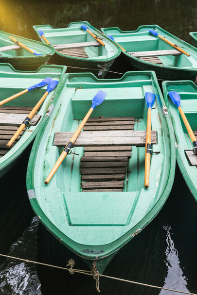 Green old empty boats with wooden oars on the lake closeup. - Photo, Image