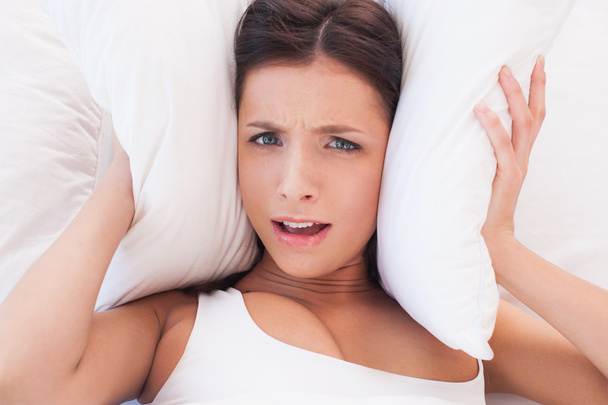 Woman covering ears by pillows - Photo, Image