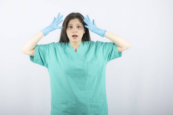 Femme médecin dans des gants médicaux montrant les mains sur fond blanc - Photo, image