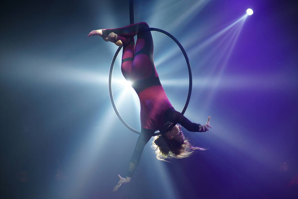 Flexibele vrouw turner ondersteboven op hoepel, circus show. Hoge kwaliteit foto - Foto, afbeelding