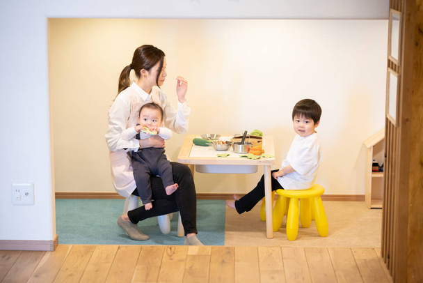 Азійська молода нянька бавиться з дітьми в приміщенні. - Фото, зображення