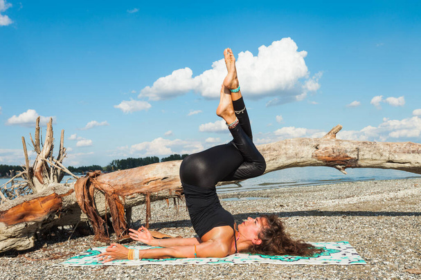 stile di vita sano giovane donna pratica yoga sulla spiaggia del fiume all'aria aperta soleggiata giornata estiva posa invertita - Foto, immagini