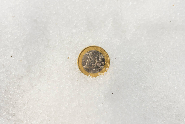 雪の上に1ユーロ硬貨のフラットレイアウト。経済危機の概念｜コピースペース. - 写真・画像