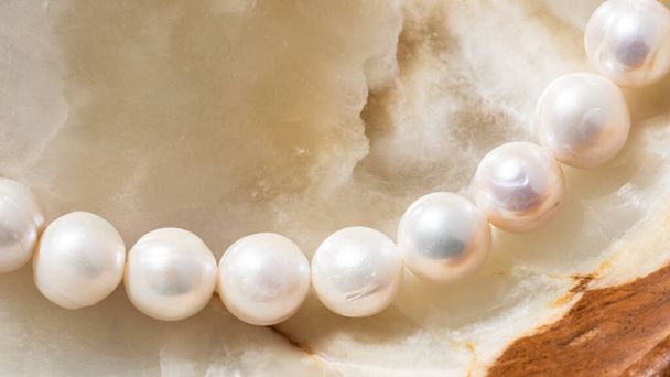 Naturaleza cadena blanca de perlas sobre fondo de mármol en enfoque suave, con reflejos - Foto, imagen