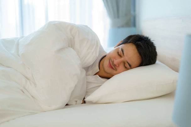 Ázsiai férfi alszik, és jó álmok fehér takaró reggel. Pihenés munka után fárasztó a hálószobában otthon - Fotó, kép