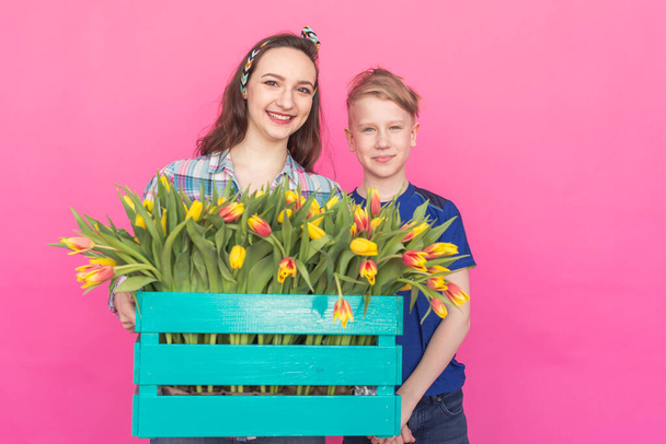 Rodina portrét sestra a dospívající bratr s tulipány na růžovém pozadí - Fotografie, Obrázek