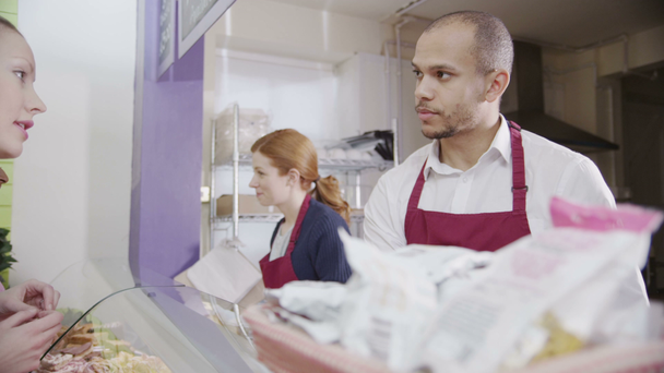tevreden klanten kiezen uit een selectie van vers gebak in een café of bakkerij - Video