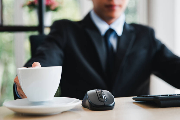 uomo d'affari che lavora con una tazza di caffè e un computer portatile in background - Foto, immagini