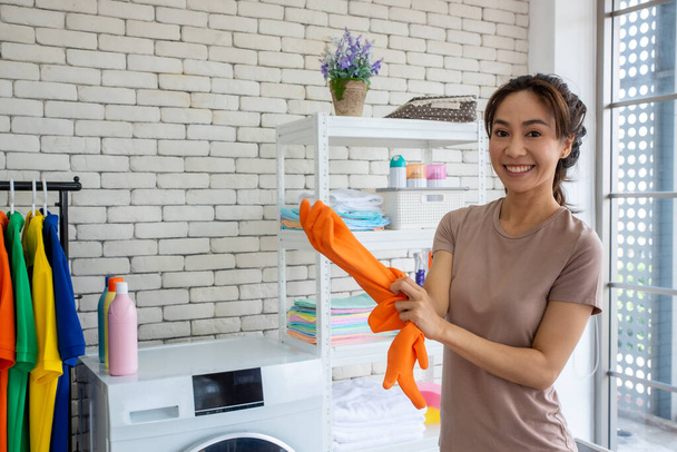 νοικοκυρά με προμήθειες καθαρισμού σε πορτοκαλί γάντια καουτσούκ  - Φωτογραφία, εικόνα