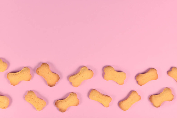 Bone shaped dog biscuits at bottom of pink background wih empty copy space - Photo, image
