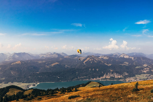 parachutiste avec son parachute coloré survole le lac Wolfgangsee en Haute-Autriche près de la ville de Salzbourg. Position de départ sur la montagne Schafberg. Jouer avec la vie. sport dangereux. - Photo, image