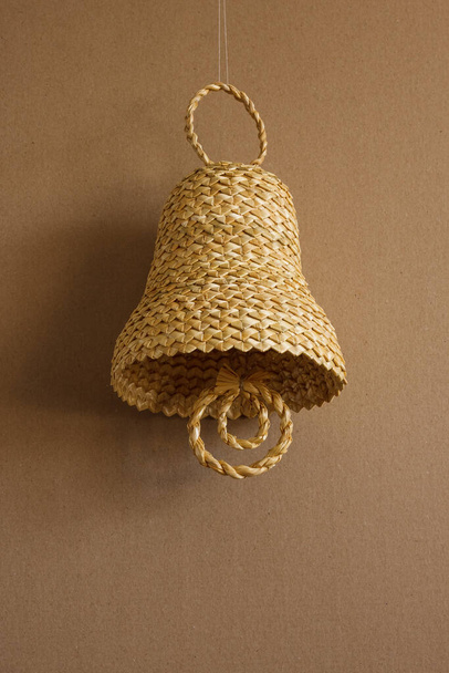 Bell made out of straw on a beige background. Straw bells decorations.  Background - Photo, Image