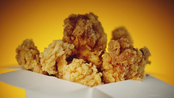 Bucket of crispy golden chicken wings, legs and strips. Side view over orange background - Footage, Video