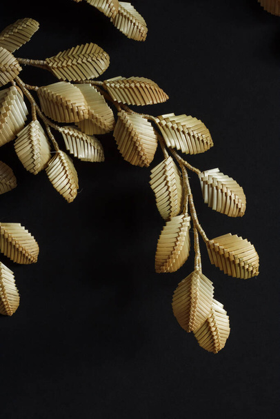Dekoration aus Stroh auf schwarzem Hintergrund. Zweige mit Blättern bestehen aus Stroh. Dekor. Fragment Nahaufnahme - Foto, Bild