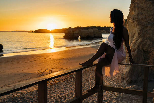 Woman sitting in a runway looking the sunset in the beach in Algarve, Portugal - Fotografie, Obrázek